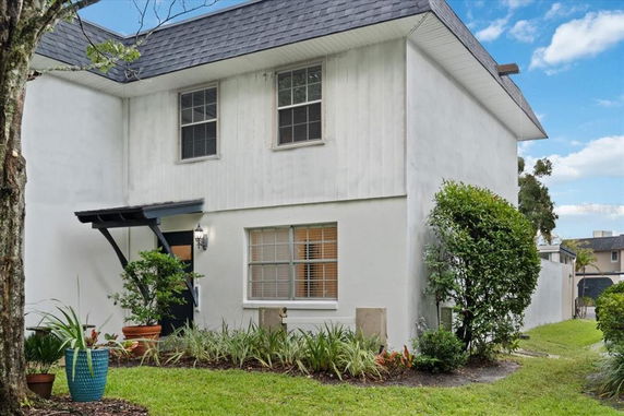 Front view of a two-story house with plants in the front yard.