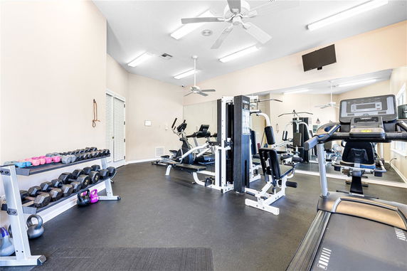Indoor gym area with exercise equipment and weights.