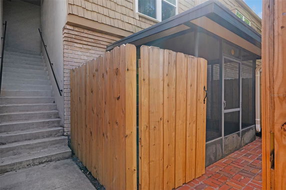 View of a residential building's exterior with wood fencing, steps leading to a higher level, and brick accents.