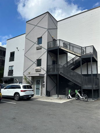 Front view of a commercial building with external staircase and parking area.