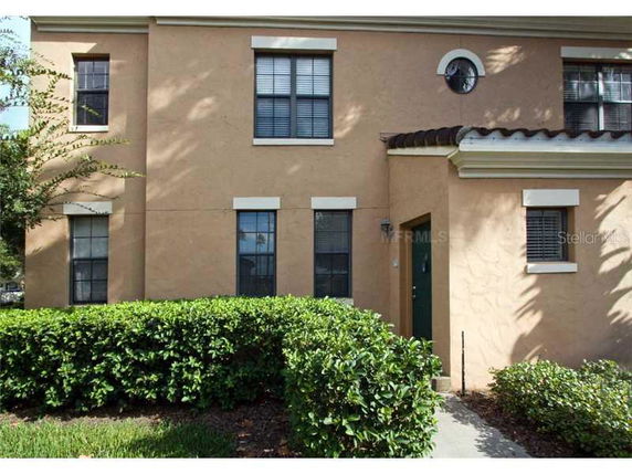 Front view of a two-story house with a beige exterior and multiple windows.