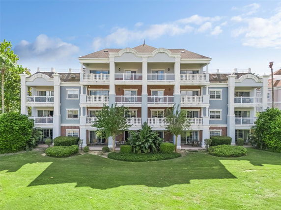 Front view of a three-story residential building with multiple balconies and a well-kept lawn.