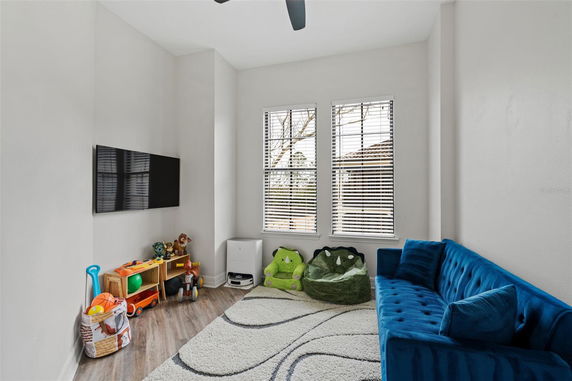 Indoor play area with a blue couch, a TV, toys, and bean bags under a window.