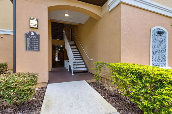Front entrance of a building with stairs and room number sign.