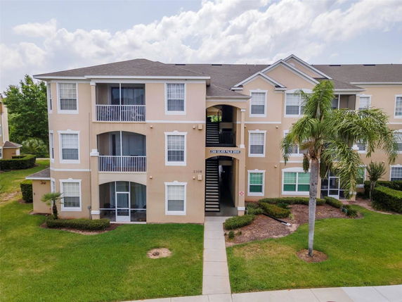 Front view of a three-story residential building with balconies and a central entrance.