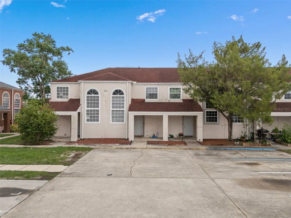 Front view of a two-story townhouse with arched windows and a red roof.