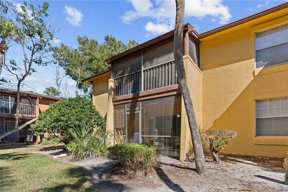 Front view of a two-story house with yellow exterior and screened balcony.