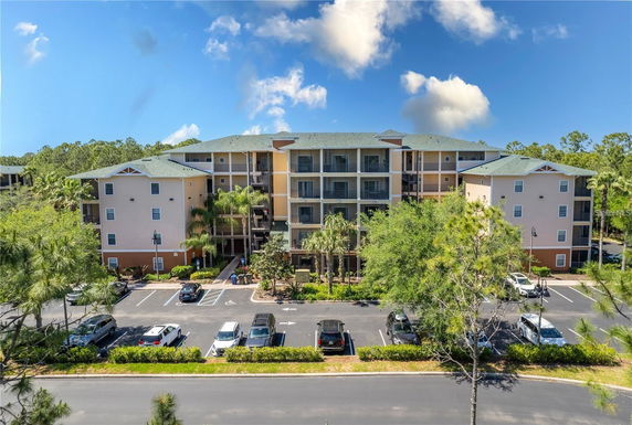 Front view of a multi-story apartment building with balconies and parking area.