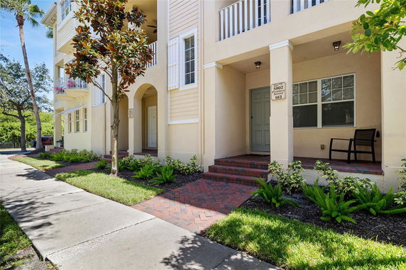 Front view of a townhouse with columns and small porch.