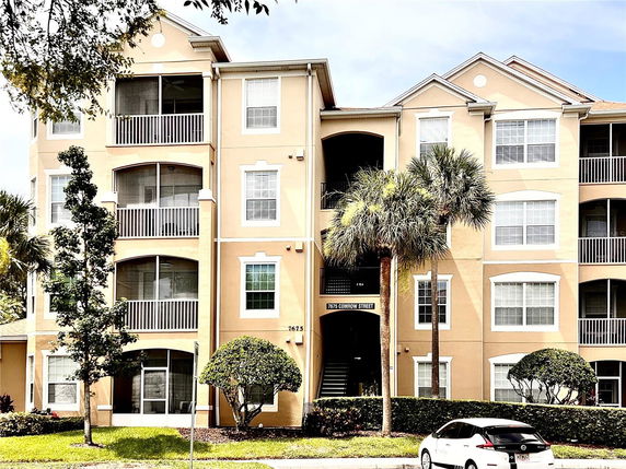 Front view of a multi-story apartment building with balconies and landscaped surroundings.