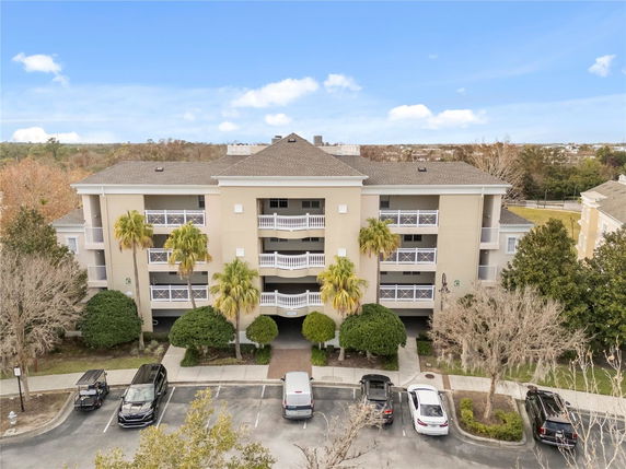 Front view of a multi-story building with balconies and a parking area.