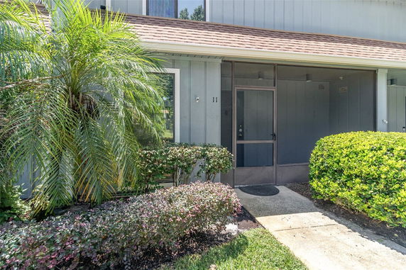 Front view of a house with a screened entrance and surrounding greenery.