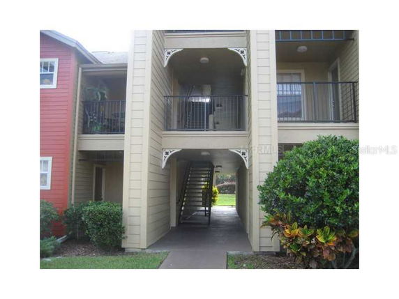 Front view of a multi-story residential building with balconies and exterior stairway.