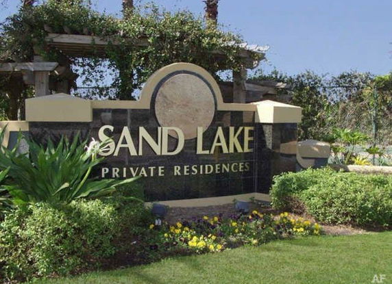 View of the entrance sign for Sand Lake Private Residences surrounded by greenery.