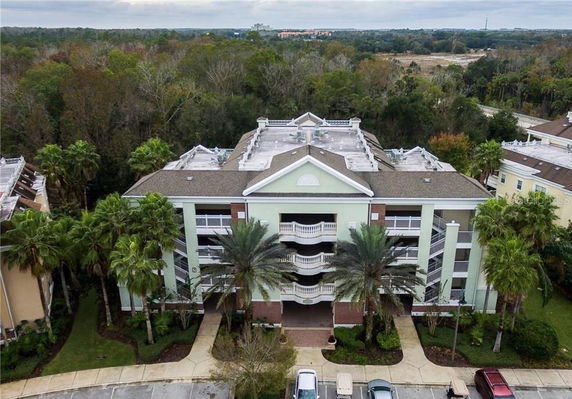 Front view of a multi-story residential building with balconies and surrounding palm trees.