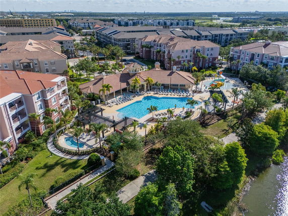 Panoramic aerial view of a residential complex with a large swimming pool and surrounding buildings.
