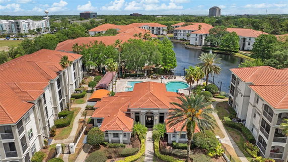 Aerial view of a residential complex with red-tiled roofs, swimming pool, and surrounding lake.