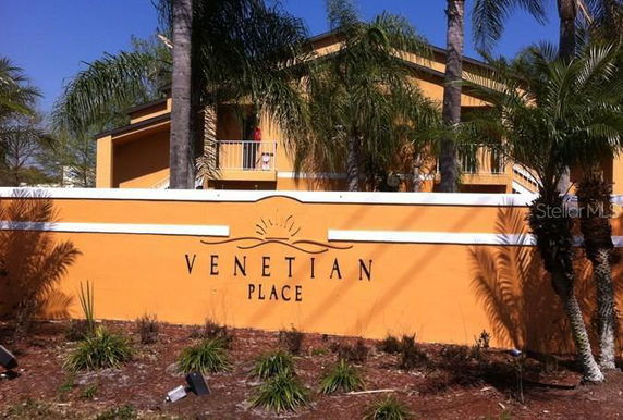 Front view of a building with a sign reading 'Venetian Place' and palm trees in the foreground.