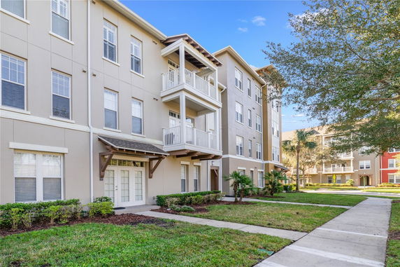 Front view of a multi-story residential building with balconies and a landscaped entrance.