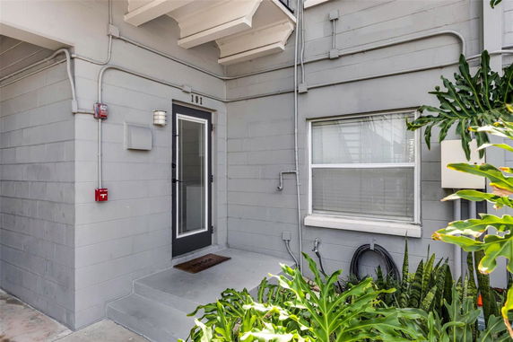Front view of a building entrance with a gray door and window.