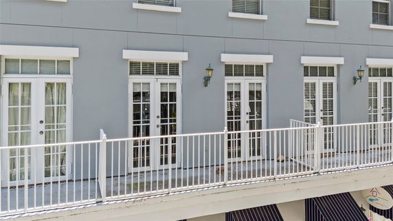 Front view of a building with multiple glass doors and a white railing.