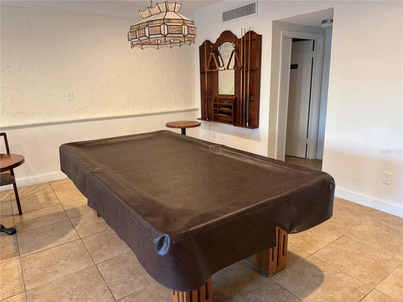 Room with a billiards table and pool cue rack on the wall.