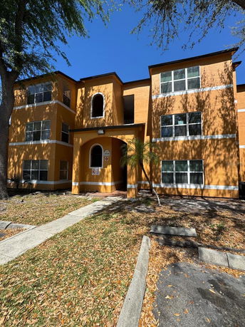 Front view of a three-story orange apartment building with white trim.