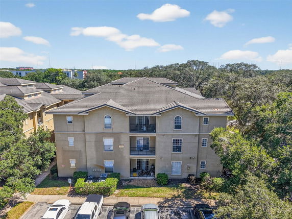 Front view of a three-story apartment building with a tiled roof and multiple balconies.