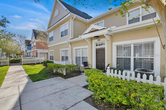 Front view of a two-story house with a picket fence and a small patio.