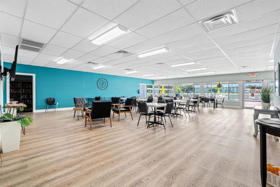 Recreational area with tables and chairs, wooden flooring, and a blue accent wall.