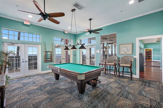 Room with a pool table and ceiling fans in a recreational area.
