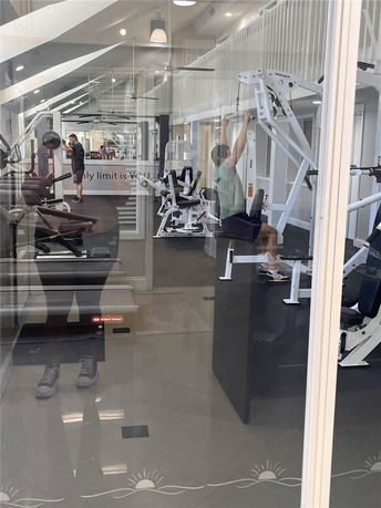 Interior view of a gym with exercise equipment and people working out.