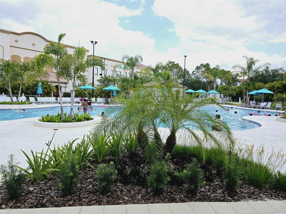 Outdoor pool area with surrounding plants and lounge chairs.