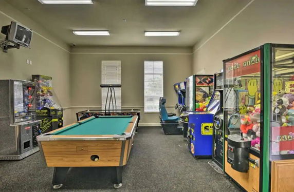 Room with arcade machines and a billiards table.