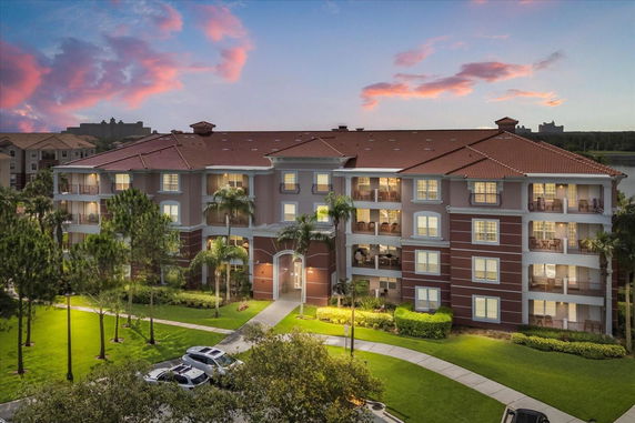 Front view of a multi-story apartment building with balconies and palm trees.