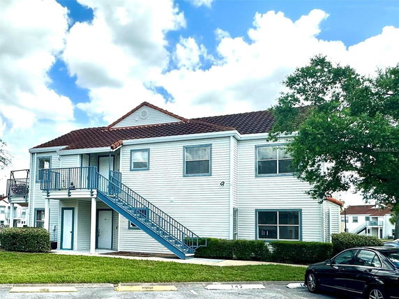 Front view of a two-story building with an external staircase and a red-tiled roof.
