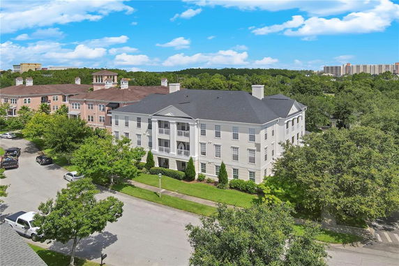 Front view of a large, three-story apartment building with a dark roof and light-colored exterior.