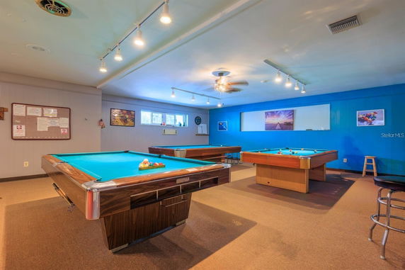 Room with multiple billiard tables and ceiling lights.
