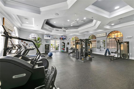 Interior view of a modern gym with exercise equipment and large windows.