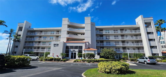 Front view of a multi-story residential building with balconies and a central entrance.