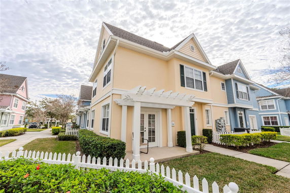 Front view of a two-story house with gable roof and white pergola at entrance.