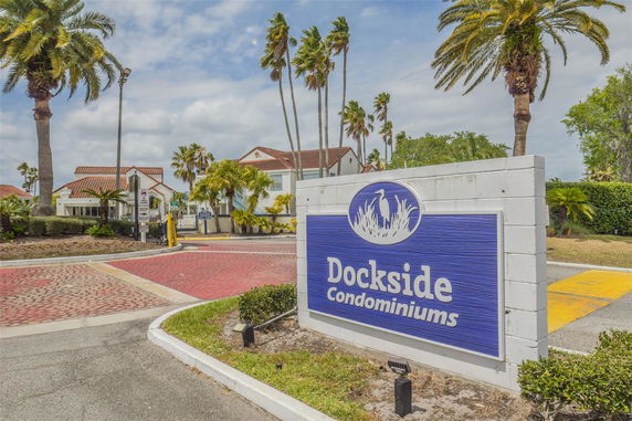 Front view of a condominium building with red-tiled roofs and palm trees in the surrounding area.