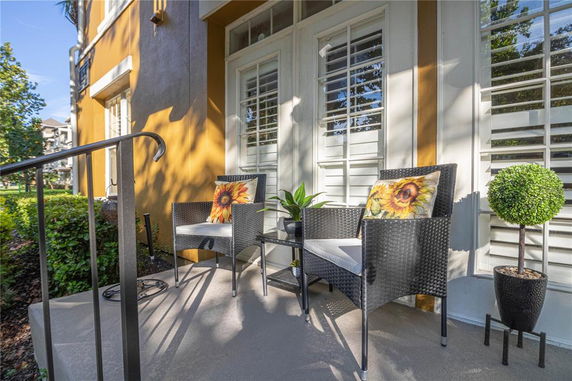 Front view of a house with a small porch featuring two chairs and a side table.