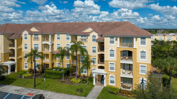 Front view of a multi-story apartment building with balconies and a tiled roof.
