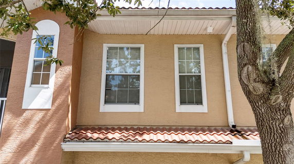Front view of a house with two windows and a partial tiled roof.