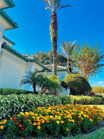 Side view of a house with a green roof and decorative plants and flowers in the foreground.