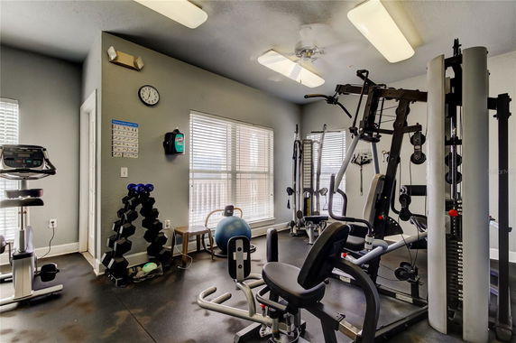 Indoor gym area with exercise equipment and weights.