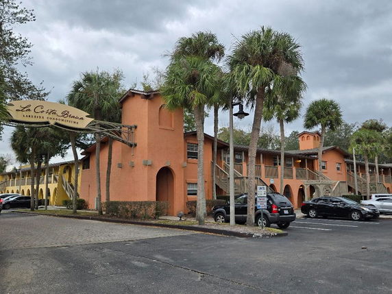 Front view of a two-story condominium complex with arched entryways and exterior staircases.