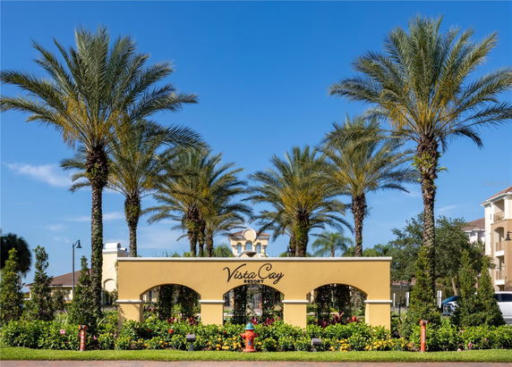 Front view of a resort entrance with palm trees and an archway.