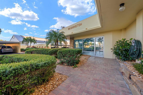 Front view of a building entrance with glass doors and a brick walkway.